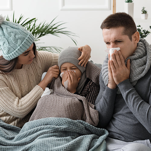 Familie mit Husten und Schnupfen auf dem Sofa